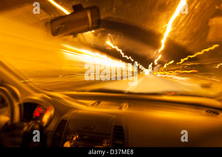 Guidare di notte in una mano sinistra guidare la macchina con le luci sfocate e velocizzando gli effetti presi dal sedile passeggeri andare veloci Foto Stock