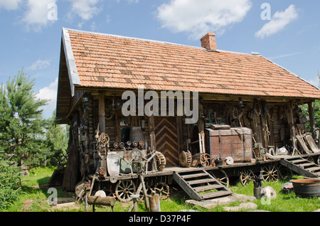 Varie retrò strumenti rurale vicino al old log in legno casa. Foto Stock