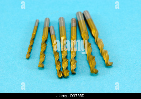 Varie dimensioni di colore dorato punte da trapano su sfondo blu. Foto Stock
