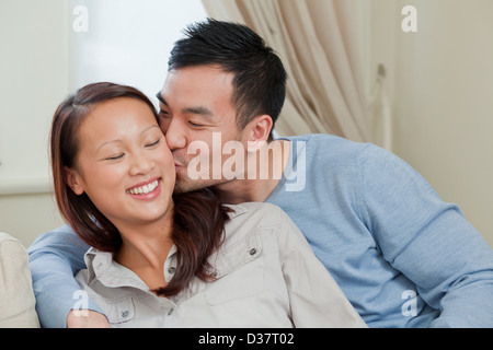 Coppia sorridente kissing sul divano Foto Stock