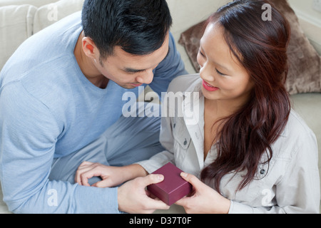 L uomo dando ragazza dono sul divano Foto Stock