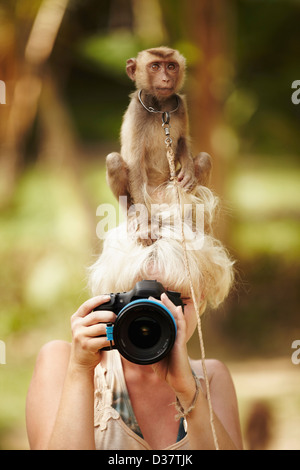 Thailandia, ritratto del fotografo femmina con scimmia macaco seduto in cima al suo capo Foto Stock