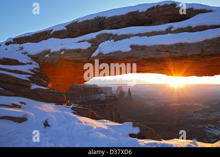 Mesa Arch coperta di neve e sunburst, Island in the Sky District, Canyonlands National Park nello Utah Stati Uniti d'America Foto Stock
