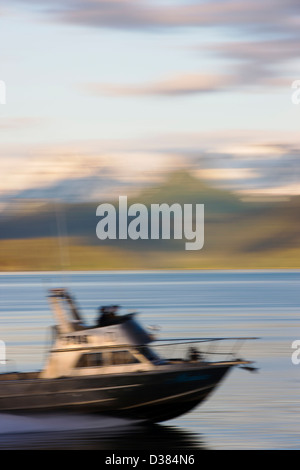 Vista al tramonto del velocizzando la barca da pesca su Kachemak Bay nei pressi di Homer Spit, Omero, Alaska, STATI UNITI D'AMERICA Foto Stock