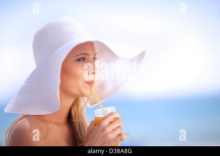 Donna in floppy hat di bere succo di frutta Foto Stock