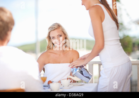 La cameriera che serve caffè donna a tavola Foto Stock