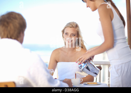 La cameriera che serve caffè donna a tavola Foto Stock