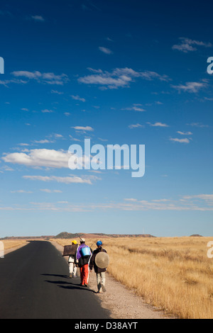 Madagascar, Ilakaka, RN7 autostrada nazionale, tre escursionisti sulla lunga strada vuota Foto Stock