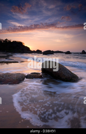 Il lavaggio delle onde sulle rocce sulla spiaggia Foto Stock