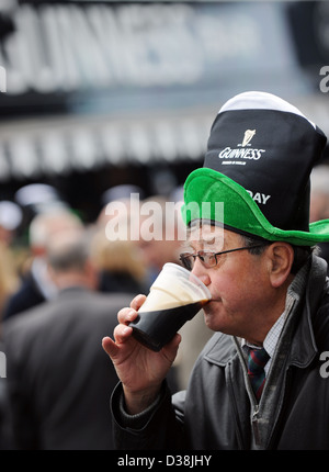 Un uomo beve una pinta di Guinness di San Patrizio giorno durante il Cheltenham horse racing festival Foto Stock