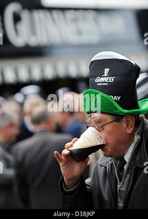 Un uomo beve una pinta di Guinness di San Patrizio giorno durante il Cheltenham horse racing festival Foto Stock