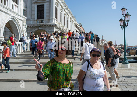 La folla di turisti attraversando un ponte sulla Riva degli Schiavoni, di fronte al Palazzo Ducale Venezia Foto Stock