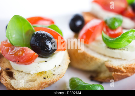 Primo piano di spaghetti con mozzarella di bufala, pomodori, olive e basilico su piastra bianca Foto Stock