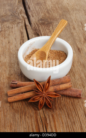 Il cinese cinque spezie in un ramekin con anice stellato e bastoncini di cannella su uno sfondo di vecchio legno stagionato Foto Stock