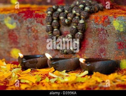 Lampade a olio e Rudraksha indiano / Japa Mala i grani di preghiera sui gradini di un rurale villaggio indiano il santuario / Tempio. India Foto Stock