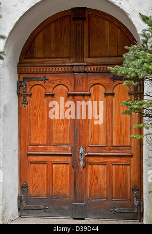 Bella doppia in legno porte, in un ambiente rustico con stucco edificio in un arco. Elemento architettonico. Foto Stock