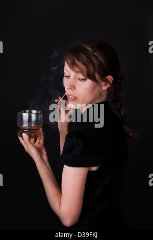 Bella donna con sigaretta elettrica e un bicchiere di Whiskey Foto Stock