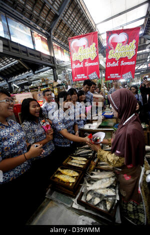 Solo, Giava centrale, Indonesia. 14 febbraio 2013. Gli studenti hanno celebrato il giorno di San Valentino con fiori e cioccolatini distribuiti agli operatori economici il 14 febbraio 2013 a Pasar Gede, Solo, Giava centrale, Indonesia. Gli studenti anche cantato una canzone mentre si cammina intorno al mercato per intrattenere i mercanti. (Immagine di credito: credito: Sijori Immagini/ZUMAPRESS.com/Alamy Live News) Foto Stock