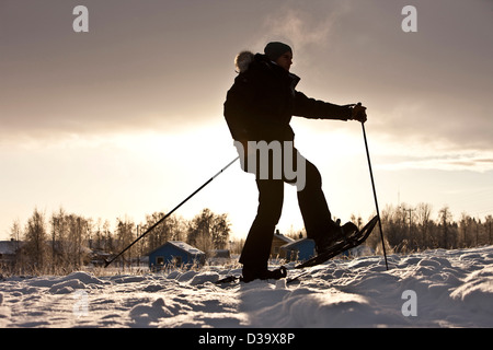 Uomo con le racchette da neve a piedi attraverso la neve, la Lapponia Foto Stock