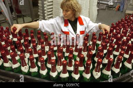 (Dpa) - Un dipendente controlla le bottiglie su una linea di imbottigliamento presso il vino spumante produttore Rotkaeppchen-Mumm in Freyburg, Germania orientale, 19 dicembre 2003. Circa trenta per cento della quantità annuale di vino spumante è venduto in novembre e dicembre. Foto Stock