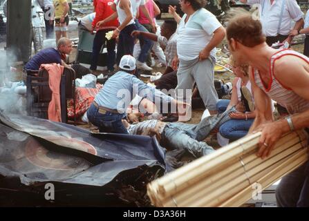 (Dpa file) - La gente prima dare un aiuto ai feriti dopo il disastroso incidente aereo durante la mostra aeronautica presso la base aerea USA a Ramstein, Germania Ovest, 28 agosto 1988. Un jet italiano del stunt-squadriglia "Frecce Tricolori" era entrato in collisione con altri due getti e in esploso, schiantarsi dentro una c Foto Stock