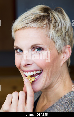 Donna sorridente mangiando snack Foto Stock