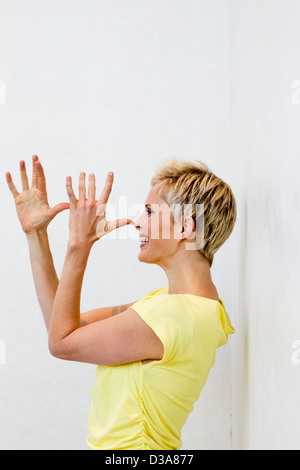 Donna sorridente rendendo il viso con le mani Foto Stock