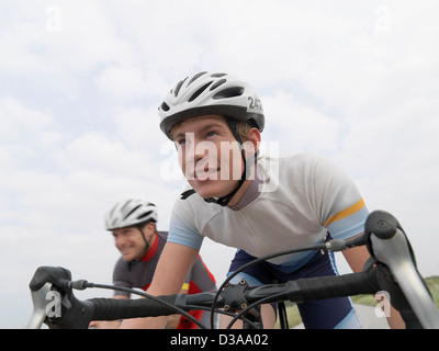 Padre e figlio ciclismo su strada rurale Foto Stock