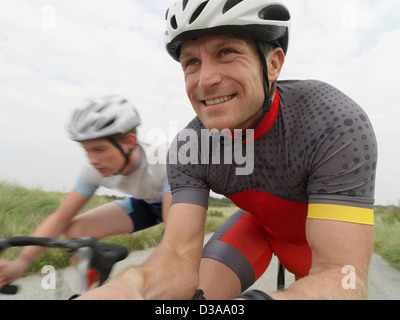 Padre e figlio ciclismo su strada rurale Foto Stock