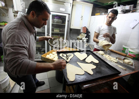 Febbraio 14, 2013 - Gaza City, nella Striscia di Gaza, Territori palestinesi - palestinesi fornai preparano pasta in forma di cuore al suo negozio il giorno di San Valentino in Cisgiordania città di Ramallah, il 14 febbraio 2013. Il giorno di San Valentino è sempre più popolare della regione come le persone che hanno preso l'abitudine di dare fiori, carte, cioccolatini e regali per innamorati per celebrare l'occasione (credito Immagine: © Issam Rimawi APA/images/ZUMAPRESS.com) Foto Stock