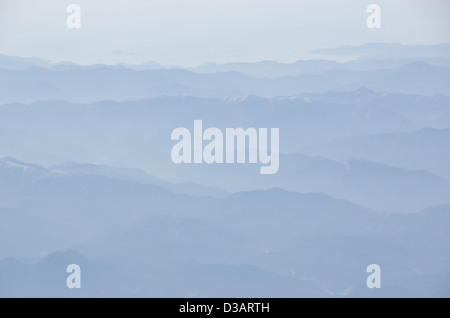 Paesaggio di montagna con nebbia e sole, contorno di montagne Foto Stock