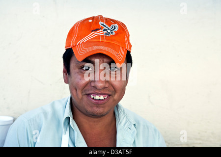 Sorridenti giovane messicano uomo venditore ambulante che indossa l'arancione cappello da baseball godendo di lavorare su una strada in Oaxaca de Juarez Mexico Foto Stock