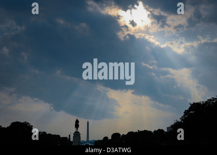 Raggi di sole brillare attraverso le nuvole scure sopra il Mall e il Monumento a Washington a Washington DC come visto dal Campidoglio. Foto Stock