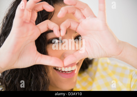Donna ispanica messa a forma di cuore con le dita Foto Stock