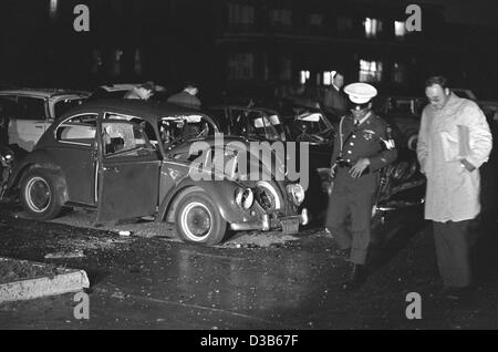 (Dpa file) - In Germania un funzionario di polizia e un ufficiale della US polizia militare raffigurato nella parte anteriore del scatafascio VW Beetle in cui una delle bombe esplose su di noi quartier generale militare a Heidelberg, Germania Ovest, 24 maggio 1972. Tre soldati americani sono stati uccisi e cinque feriti quando due bombe Foto Stock