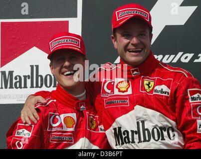 (Dpa) - Brasiliano pilota di Formula 1 Rubens Barrichello (R) e la sua Ferrari del team mate, il tedesco Michael Schumacher, di allegria oltre la loro doppia vittoria dopo il Gran Premio di Ungheria sul circuito di Hungaroring vicino a Budapest, Ungheria, 18 agosto 2002. Barrichello ha vinto il primo posto e Schumacher è arrivato secondo. Foto Stock