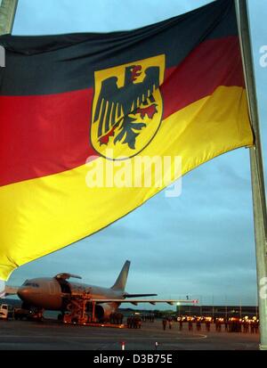 (Dpa) - La bandiera tedesca è su metà-montante come le bare contenenti i corpi dei soldati tedeschi arriva a bordo di una forza aerea aereo presso l'aeroporto di Colonia, Germania, 25 dicembre 2002. I sette soldati tedeschi sono stati uccisi in un incidente in elicottero il 21 dicembre in Afghanistan. Essi sono serviti sul Foto Stock