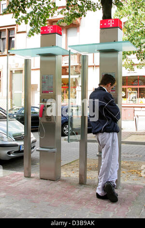 (Dpa) - l'immagine, datata 30 giugno 2005, mostra un giovane uomo che utilizza un telefono pubblico booth fornito dalla comunicazione tedesco compagnia Telekom in Frankfurt Main, Germania. Foto Stock
