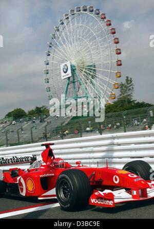 (Dpa) - tedesco di formula one champion Michael Schumacher gare passato una ruota panoramica di una vicina fiera del divertimento, durante un corso di formazione a Suzuka, in Giappone, 11 ottobre 2002. Foto Stock