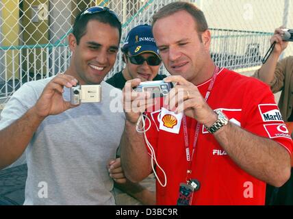 (Dpa) - Brasiliano pilota di Formula Uno Rubens Barrichello (R) colombiano e il pilota di Formula Uno Juan Pablo Montoya intrattenersi con fotocamere digitali in vista del Gran Premio del Giappone a Suzuka, in Giappone, 10 ottobre 2002. Foto Stock