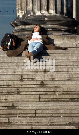 (Dpa) - Una giovane donna savours crogiolarsi al sole sui gradini della Altes Museum (museo vecchio) di Berlino, 20 gennaio 2003. Con temperature prossime a 8 gradi Centigradi (46 gradi Fahrenheit) e frizzante sunshine, alcuni vengono attirati all'aperto per godere di Berlino Meteo invernali. Foto Stock