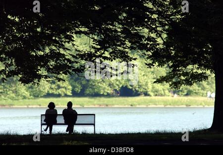 (Dpa) - un giovane si siede su un banco di lavoro in corrispondenza di un lago in un parco e gode della calma di Colonia, Germania, 25 giugno 2003. Foto Stock