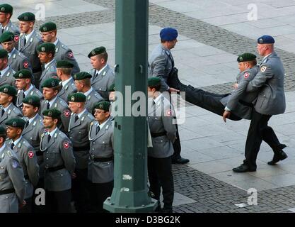 (Dpa) - due soldati tedeschi a portare via un inconscio compagno soldato da una parata di formazione durante il cerimoniale pubblico pegno e tatuaggio di esercito tedesco reclute di fronte al municipio di Amburgo, Germania, 16 giugno 2003. È la prima volta in 25 anni che i soldati pegno pubblicamente un giuramento in Foto Stock