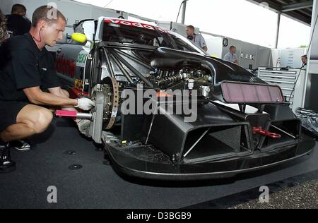 (Dpa) - Un meccanico di viti sulla ruota di una Mercedes vettura da corsa in Nuremberg, Germania, 22 giugno 2003. La vettura appartiene al pilota Mercedes Bernd Schneider. La Deutschen Tourenwagen Masters (DTM) (tedesco touring car masters) continuerà con la quinta eseguire nella stagione 2003 il 22 giugno 2003. Schneider Foto Stock