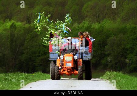 (Dpa) - Una famiglia a fare un giro su un trattore decorata con un piccolo " albero " durante la tradizionale festa del lavoro escursione in Mandelbachtal, Germania, 1 maggio 2003. Foto Stock