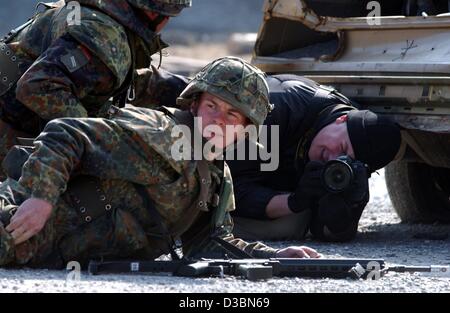 (Dpa) - Un fotografo kneenls verso il basso nella parte anteriore di un soldato e prende una foto durante un esercizio militare dell'esercito tedesco a Hammelburg, Germania, 21 marzo 2003. Entrambi i fotografi sono i partecipanti su un programma che è organizzata dall'esercito tedesco e il tedesco stampa media Association, la BERU Foto Stock