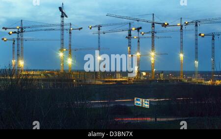 (Dpa) - Numerose gru illuminted tratto nel dusky sky sul sito della costruzione del nuovo stadio Allianz Arena di Monaco di Baviera, Germania, 1 aprile 2003. La architetti svizzeri Jacques Herzog e Pierre de Meuron progettato il nuovo stadio sportivo a nord di Monaco di Baviera. Essi hanno anche vinto il Ospiti int Foto Stock