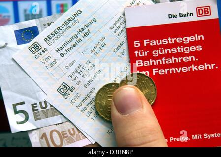 (Dpa file) - Una mano trattiene i biglietti del treno, un opuscolo della Deutsche Bahn e le banconote in euro e qualche cambiamento nella parte anteriore di un biglietto distributori automatici presso la stazione ferroviaria principale di Colonia, 25 novembre 2002. Dopo nuove tariffe per i biglietti sono stati introdotti nel dicembre 2003, il fatturato nel biglietto del passeggero sales pl Foto Stock