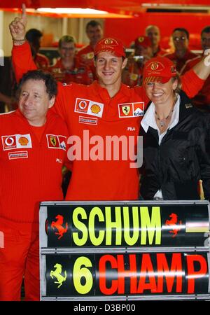 (Dpa) - Tedesco pilota di Formula Uno Michael Schumacher della Ferrari (C) festeggia con la moglie Corinna (R) e Jean Todt (L) dopo la graffatura del campionato mondiale a seguito del giapponese di FORMULA ONE Grand Prix di Suzuka, 12 ottobre 2003. Schumacher posto 8th, conquistando un record sesto mondiale champi Foto Stock