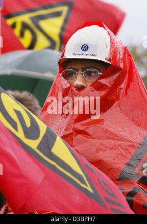 (Dpa) - ThyssenKrupp onde steelworker un rosso della IG Metall bandiera e dimostra sotto la pioggia battente per i salari più elevati, in corrispondenza di un cancello in fabbrica a Duisburg in Germania, 7 ottobre 2003. Gli operai di diverse imprese hanno preso parte in sciopero del metallo tedesco lavoratore dell'Unione IG Metall (IGM). Foto Stock